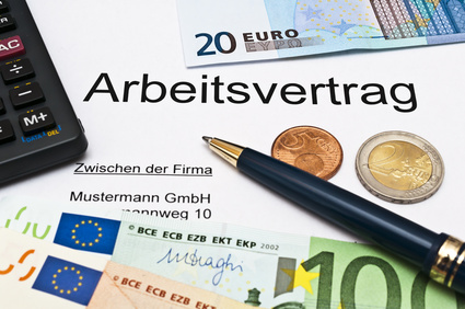Geld, Schreibunterlagen und der Schriftzug Arbeitsvertrag