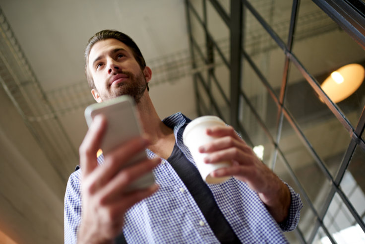 Mann mit Smartphone unterwegs im Büro