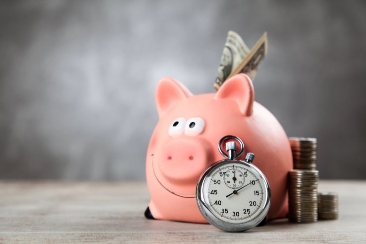 Symbolbild für Zeit-ist-Geld: Sparschwein, Geld und Stopuhr