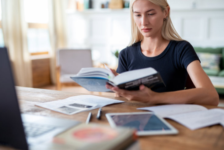 Studentin mit Buch, Tablet und Notebook