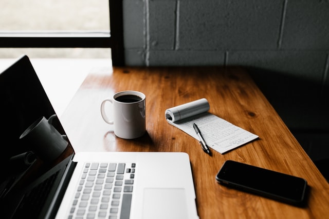 Schreibtisch mit Laptop, Smartphone und Notizblock